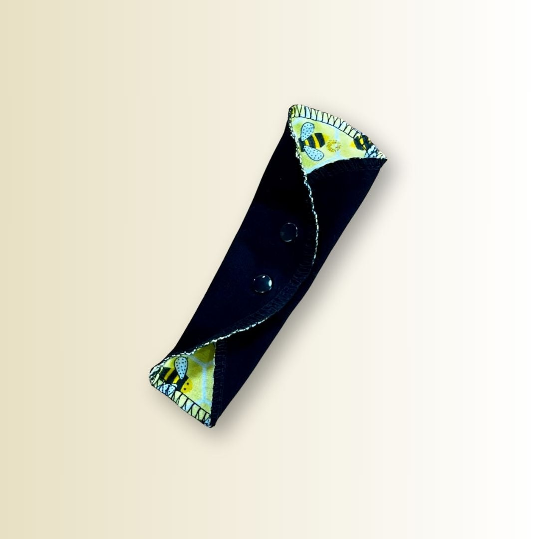Single reusable thong panty liner in yellow bee print cotton, shown open flat