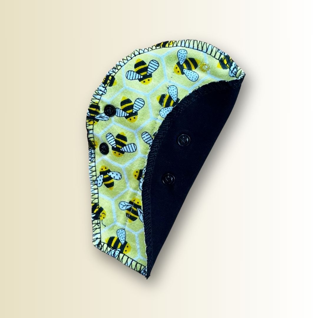 Folded bee print thong pad showing snap closure and PUL waterproof backing