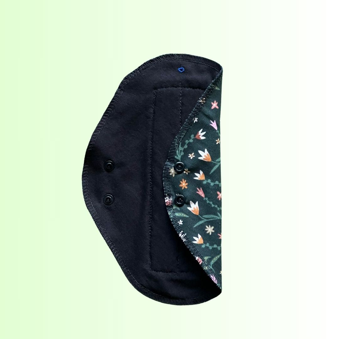 Inside view of floral green reusable pad showing soft black knitted cotton absorbent side