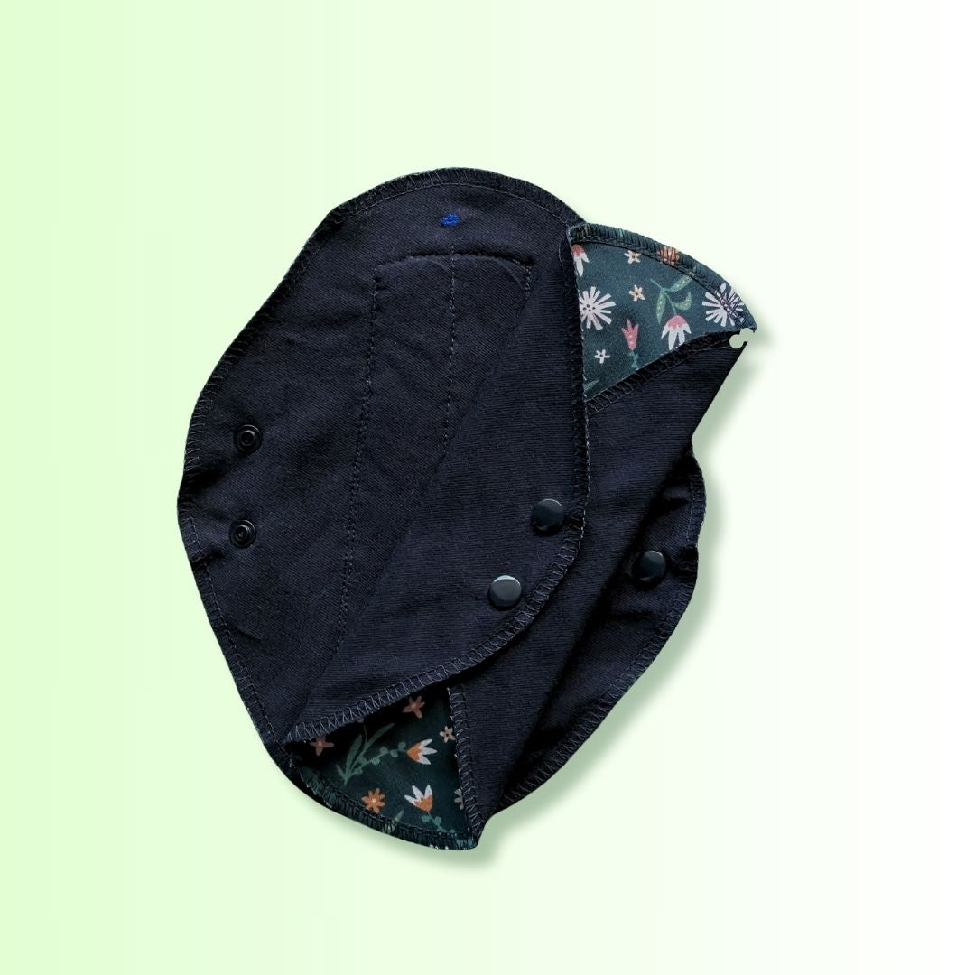 Close-up of Hume's day pad showing soft black absorbent cotton layer with floral green edge detail