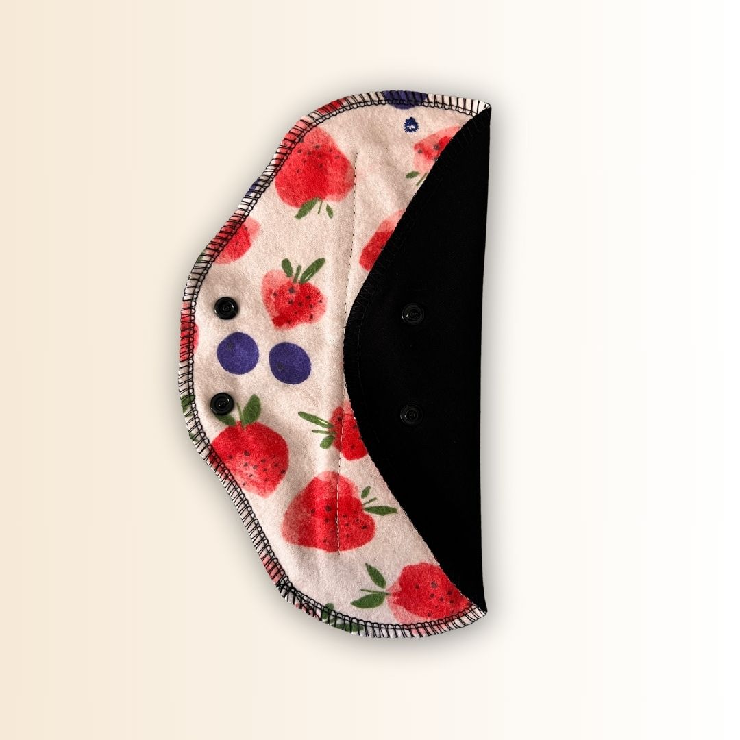 Reusable day pad with strawberry print – shown open with one wing folded.