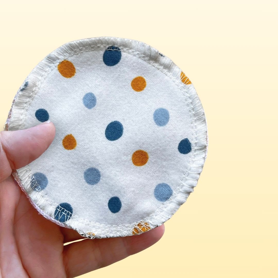 Hand holding a reusable cotton flannel face pad with multicolor polka dots – soft and eco-friendly skincare alternative