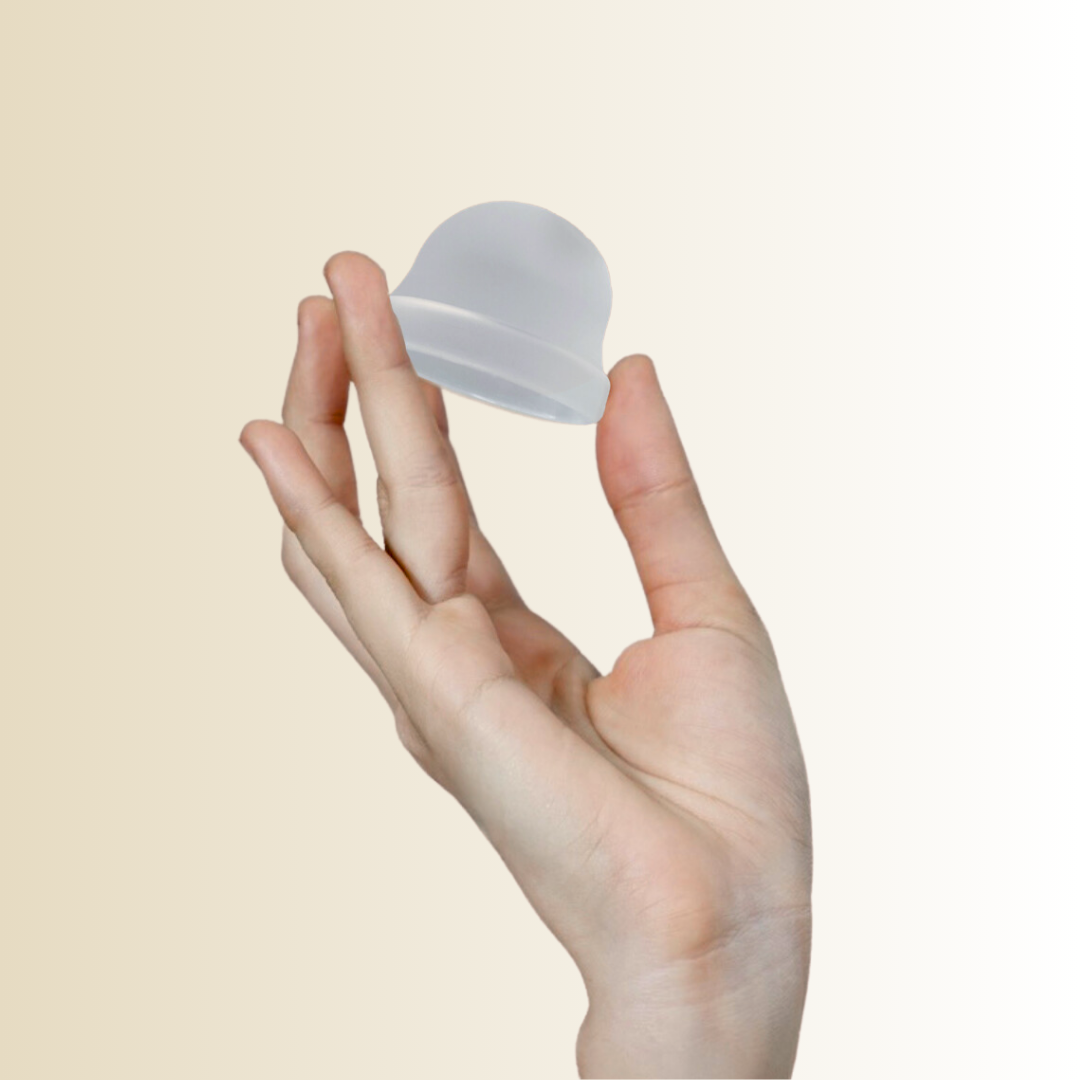 Hume’s clear menstrual disc floating above fingers – close-up of reusable period disc.