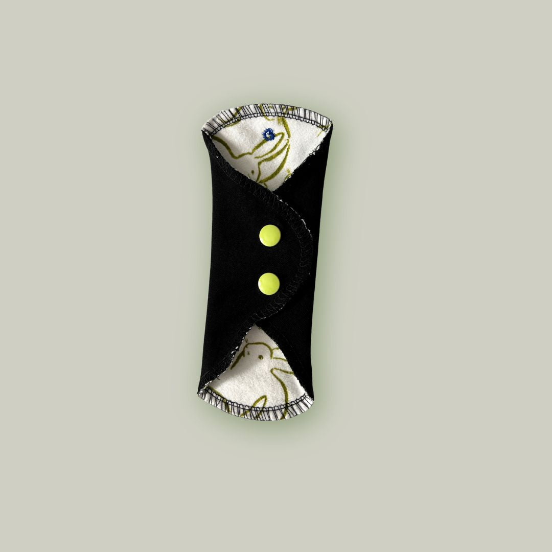 Reusable teen menstrual pad with bunny print shown closed with black wings and color snaps – Hume’s Period Care