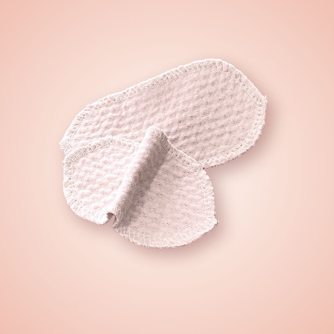 Reusable pink interlabial pad made from organic cotton, pinched center and laid flat for size reference