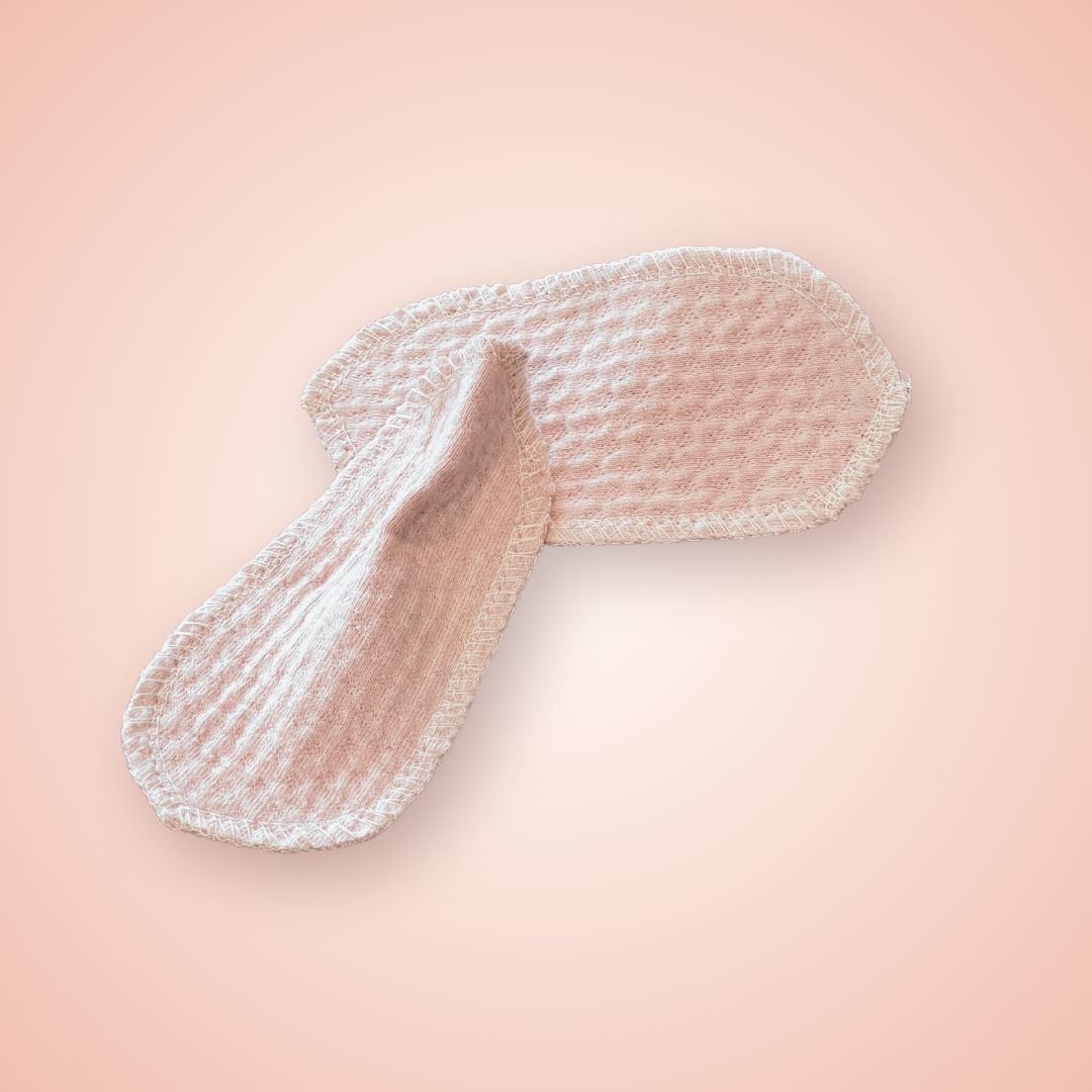 Pair of reusable organic interlabial pads with textured cotton design, shown overlapping.