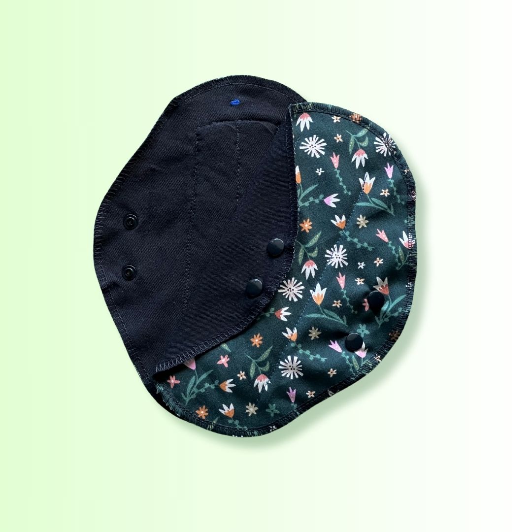 Hume’s day pad open showing both floral print outer layer and black cotton absorbent side