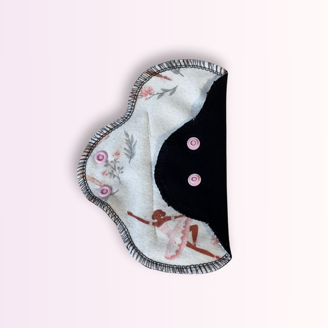 Hume’s ballerina teen pad showing black absorbent side with pink snaps. Reusable and washable cloth pad for teens.
