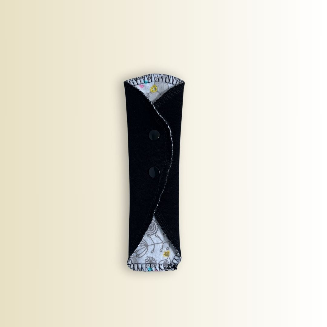 Folded thong liner with black exterior and visible hippo print edges. Compact and reusable cloth panty liner.