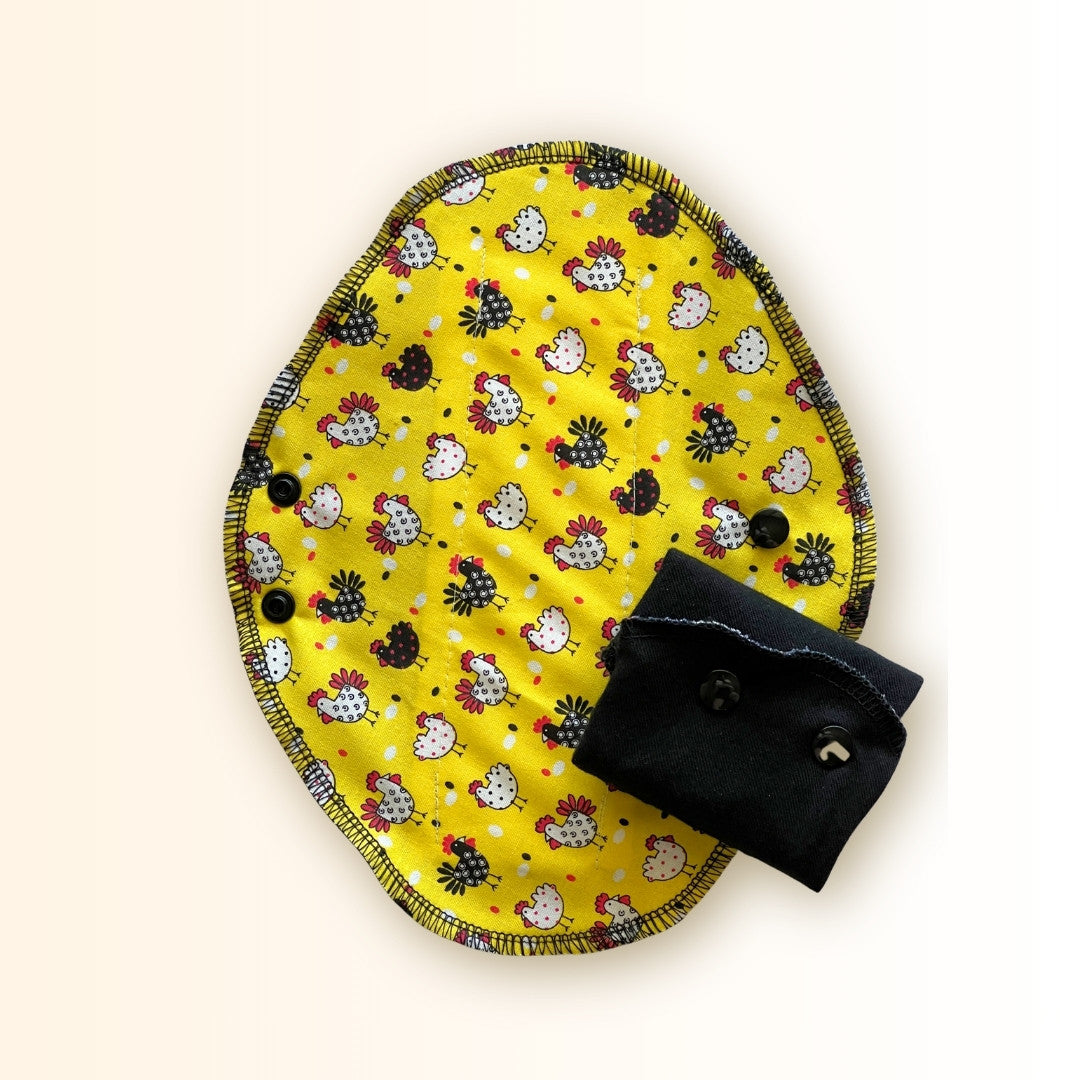 Yellow chicken reusable period pad showing the black cotton absorbent side with folded chicken print detail and snap wings from Hume’s Period Care.