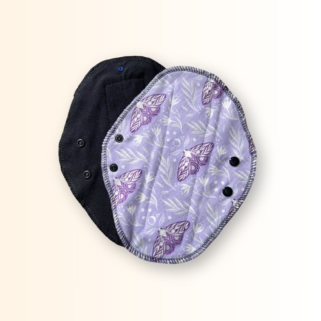 Lavender reusable cloth day pad shown with its soft black absorbent side and snap wings.