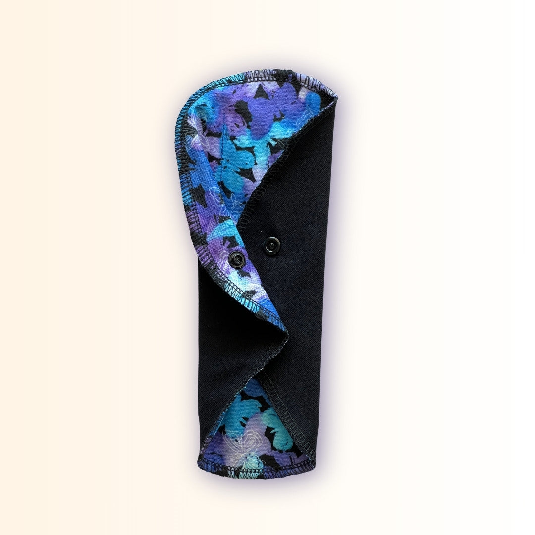 Blue Butterfly Reusable Period Pad standing folded with black cotton absorbent side, snap closure, and colorful butterfly print from Hume’s Period Care.