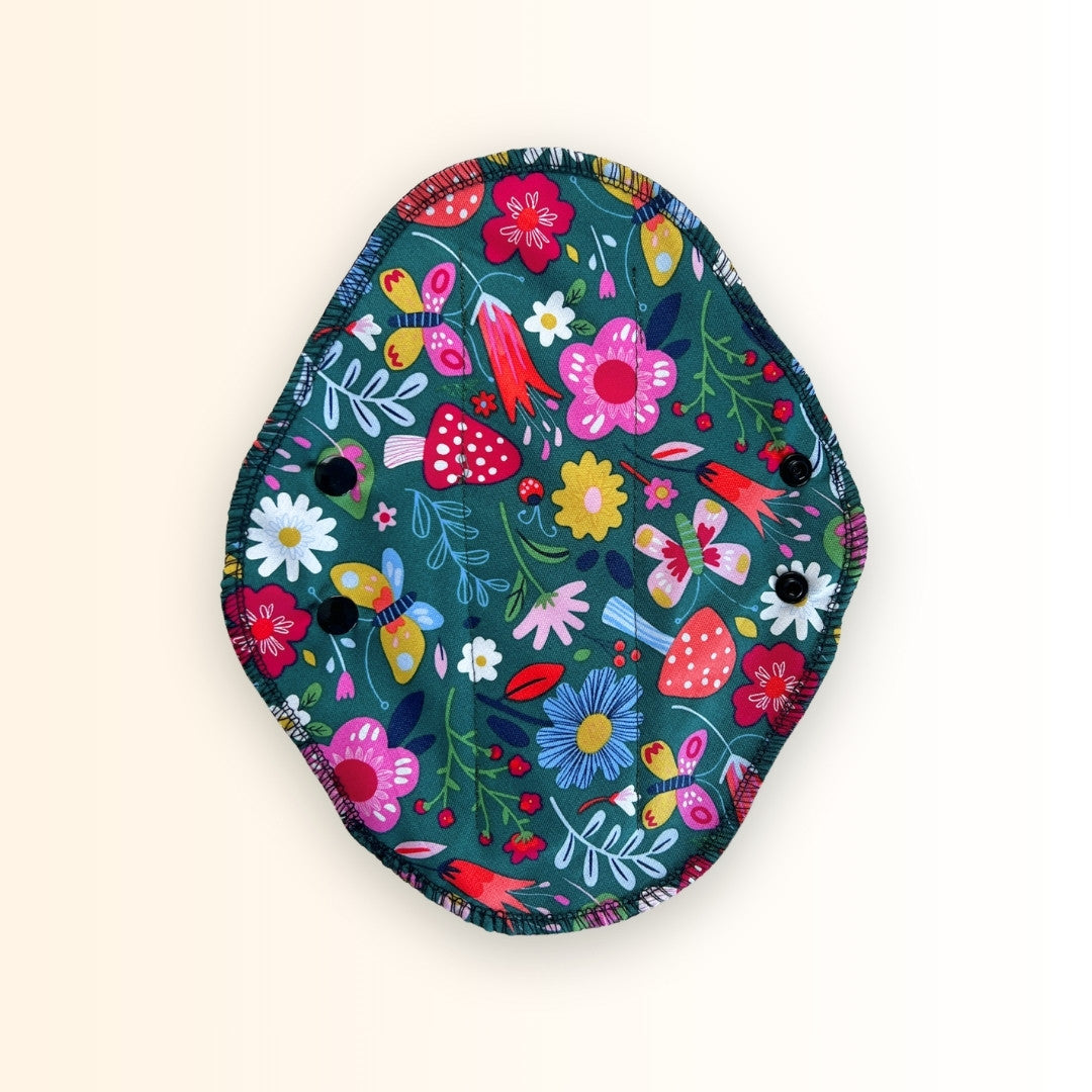 Bright floral reusable cloth pad with black absorbent cotton side.