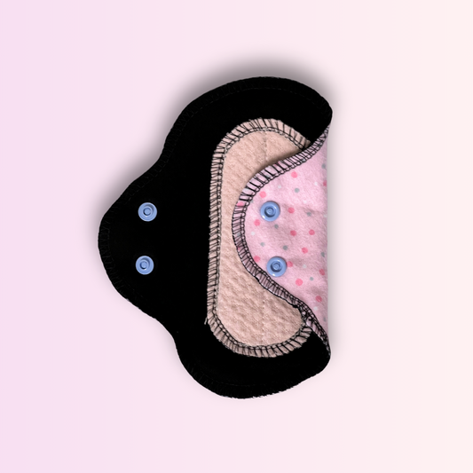 Reusable day pad with pink polka dot pattern and black wings open – eco-friendly cloth pad for light to heavy flow