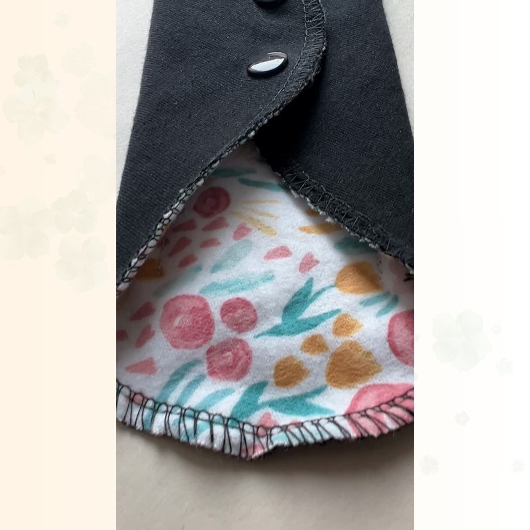 Close-up of the floral fabric, black absorbent side, snap closure, and stitching on a reusable cloth pad.
