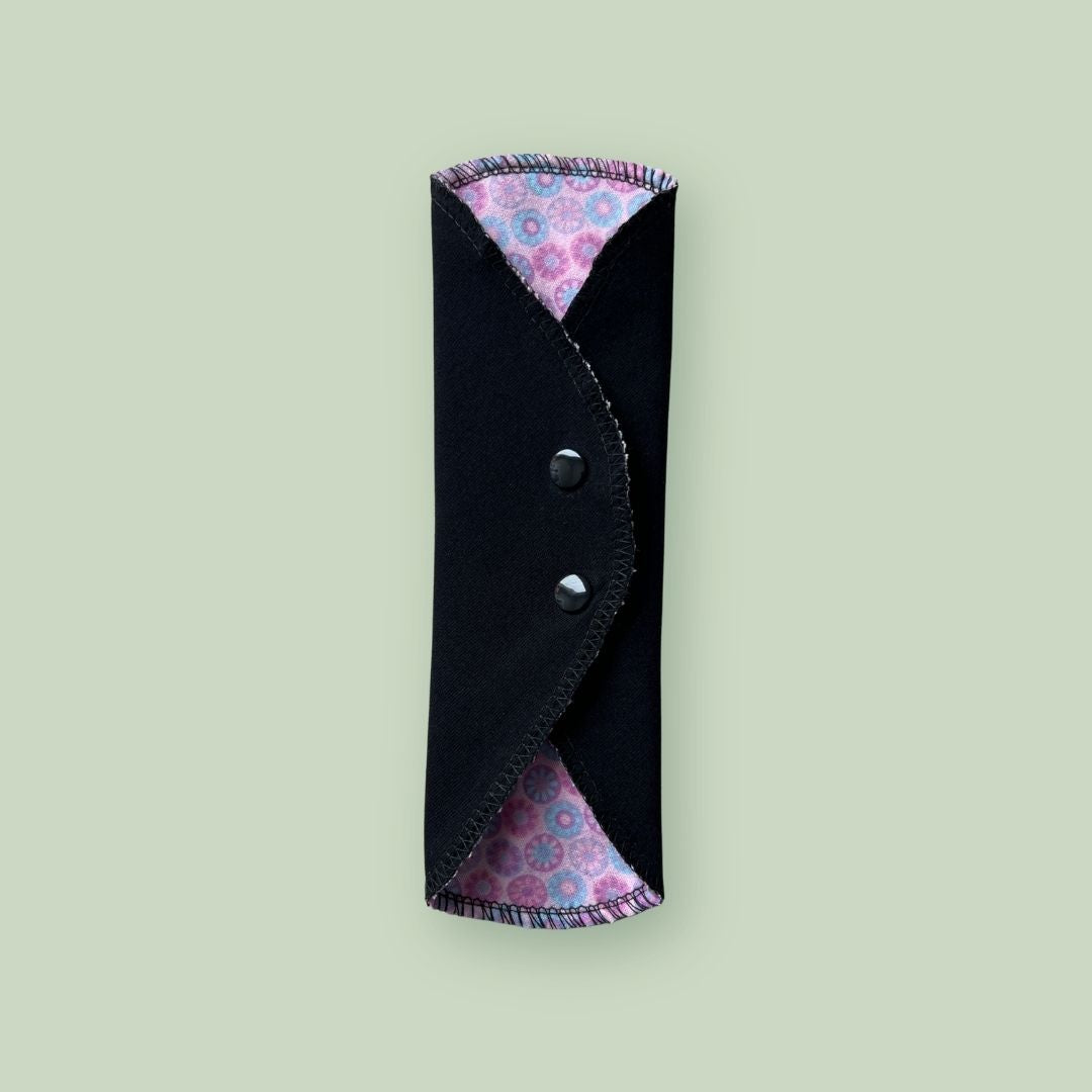 Reusable cloth pad folded and snapped for compact storage in a bag or backpack.
