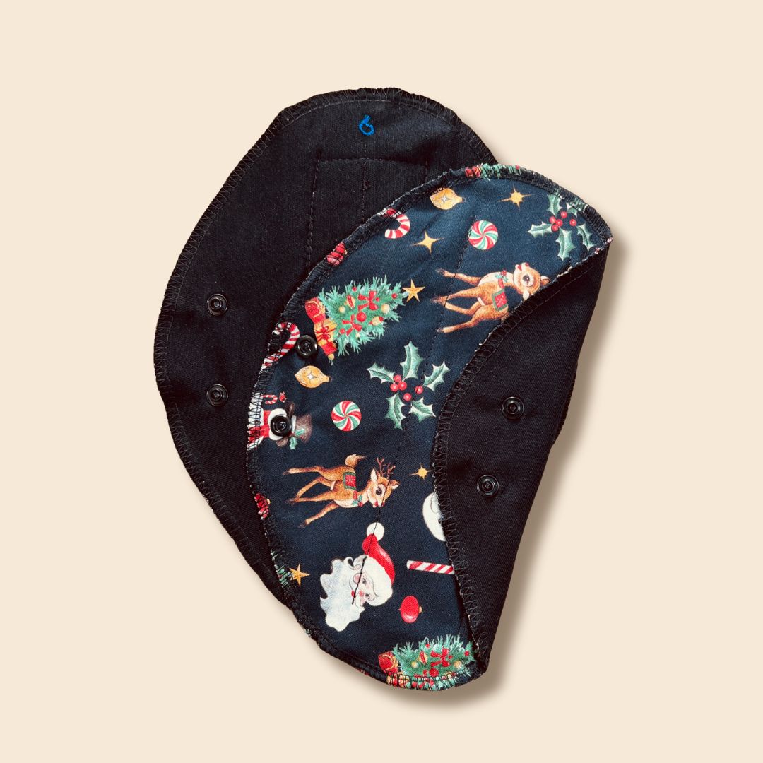 Reusable pad with Santa and reindeer print snap-wing detail.