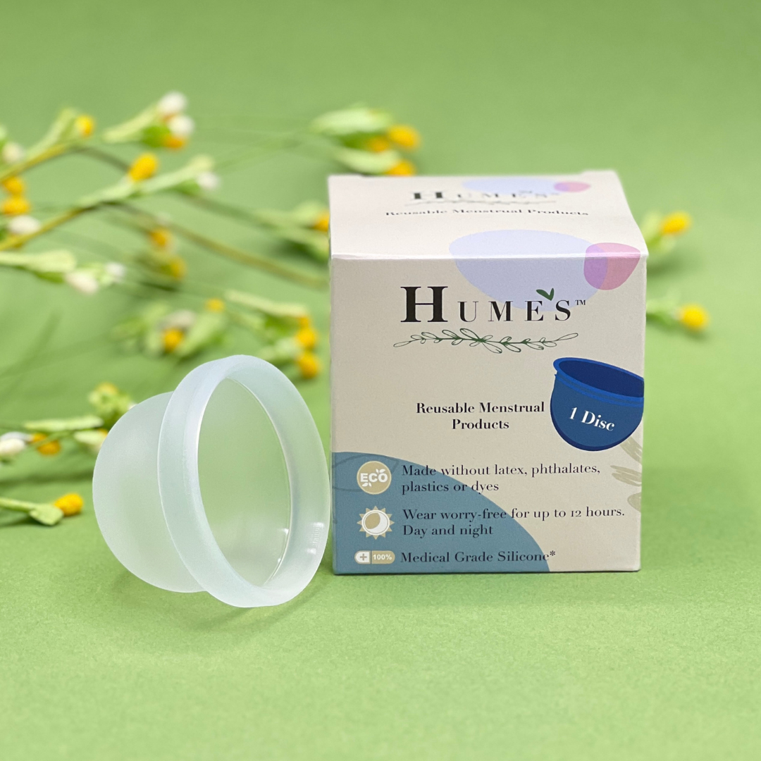 Hume’s menstrual disc shown next to product box on floral green background – eco-friendly reusable period product.