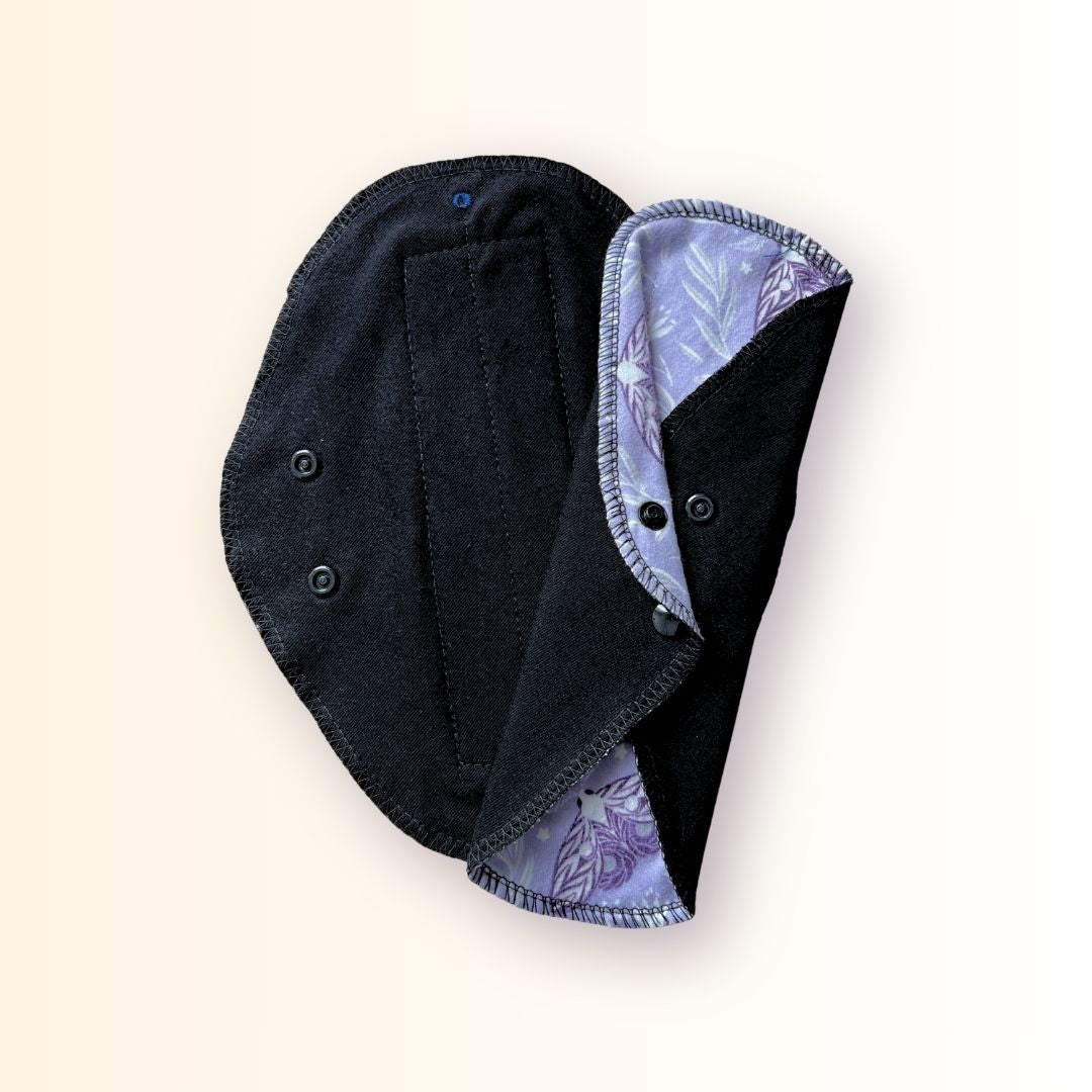 Lavender moth reusable cloth pad folded and snapped for compact storage in a bag or travel wrapper.