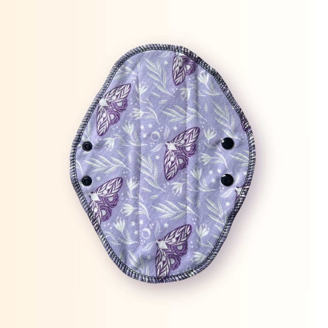 Full lavender moth print side of a reusable cloth day pad with adjustable snap wings.