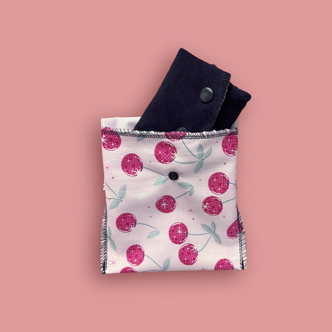 Cherry print reusable cloth pad stored inside matching carry pouch