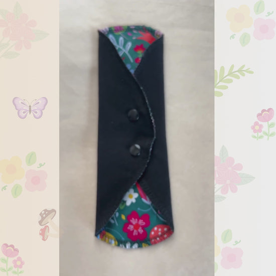 Video showing the Colorful Garden reusable day pad with floral print, snap wings, and black cotton absorbent side.