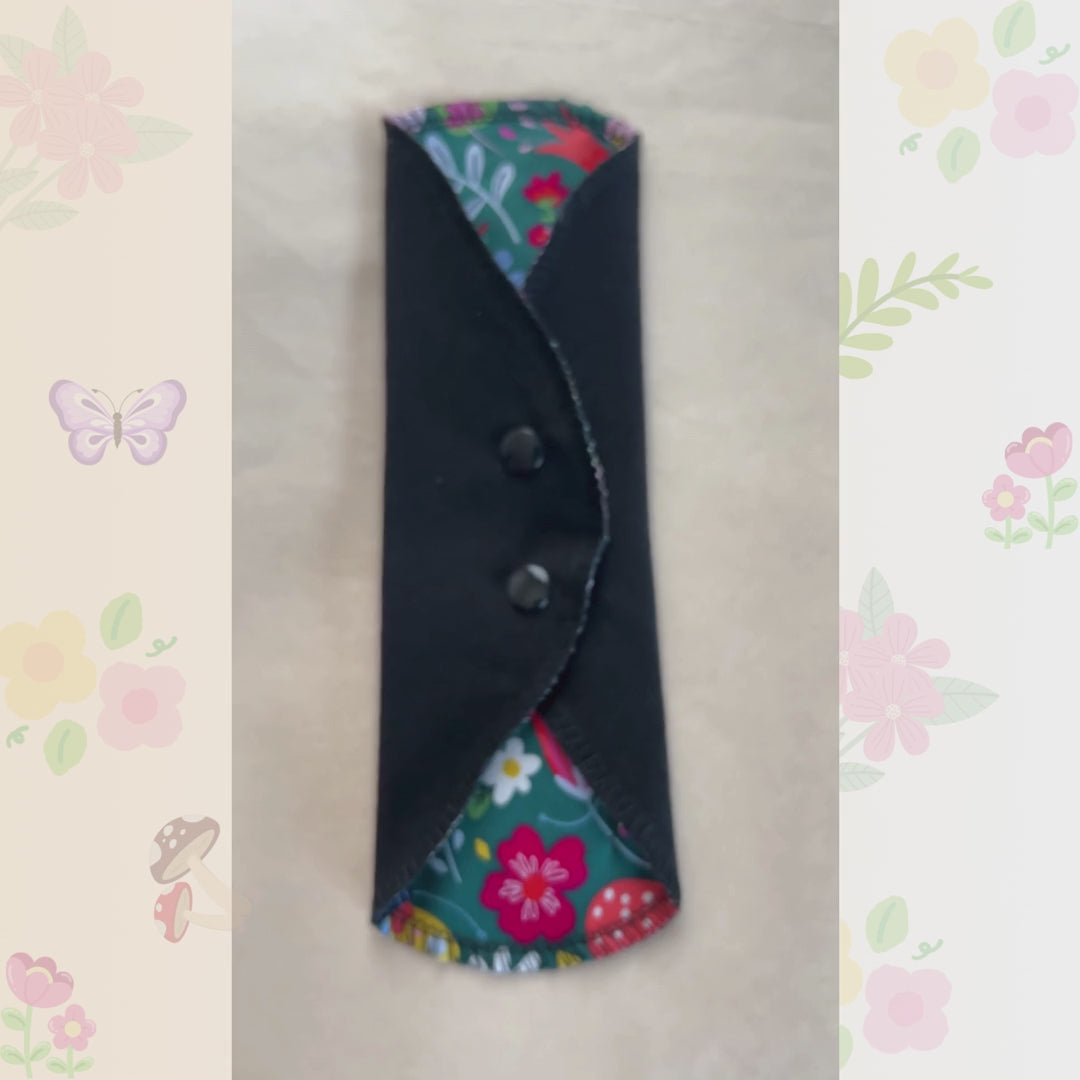 Video showing the Colorful Garden reusable day pad with floral print, snap wings, and black cotton absorbent side.