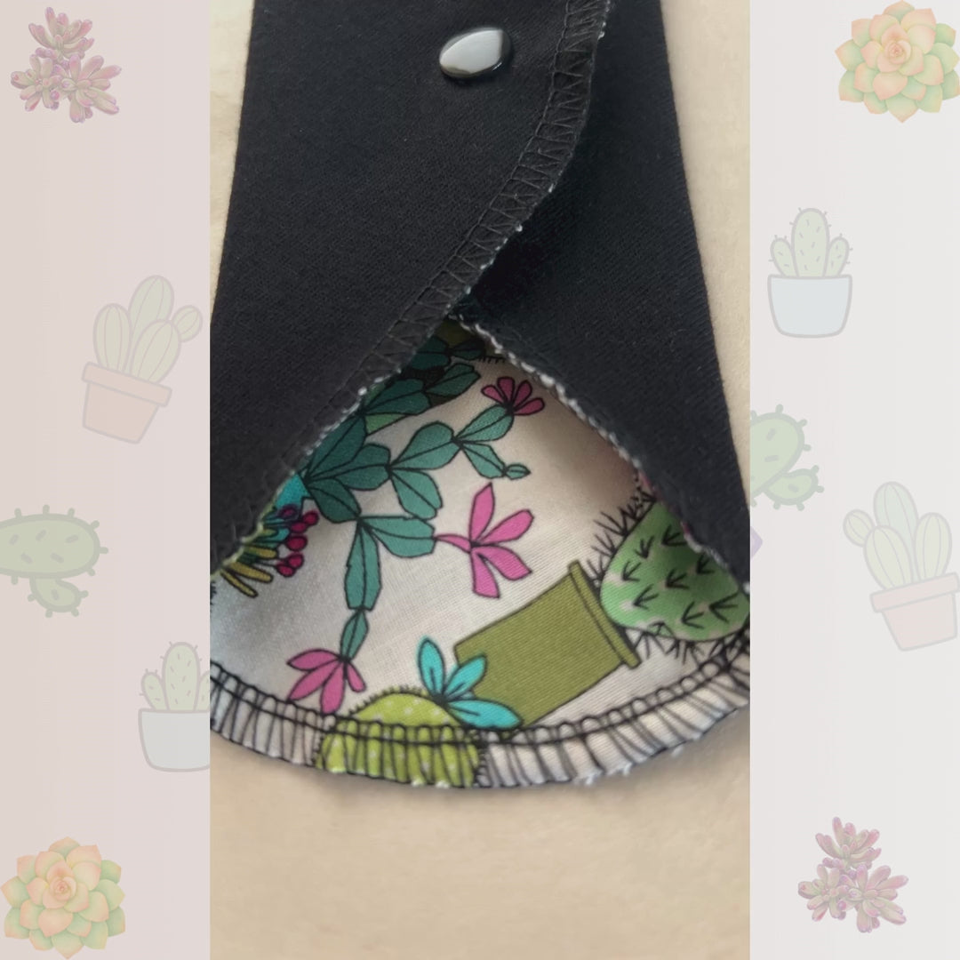 Video showing the Cactus Bloom reusable day pad with cactus print, snap wings, and black cotton absorbent side