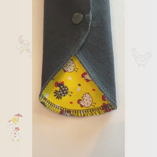 Video showing the Yellow Chicken Reusable Period Pad from Hume’s Period Care with bright yellow chicken print, black cotton absorbent side, snap wings, and washable cloth pad design.
