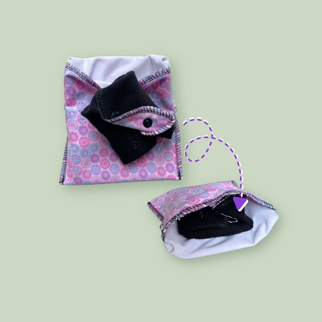 Reusable cloth pads being folded and stored inside a snap travel wrapper.