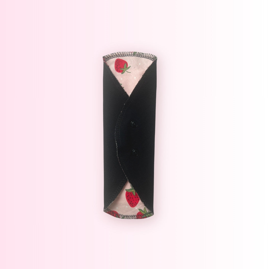 Strawberry cloth menstrual pad snapped closed to show how it wraps around underwear.