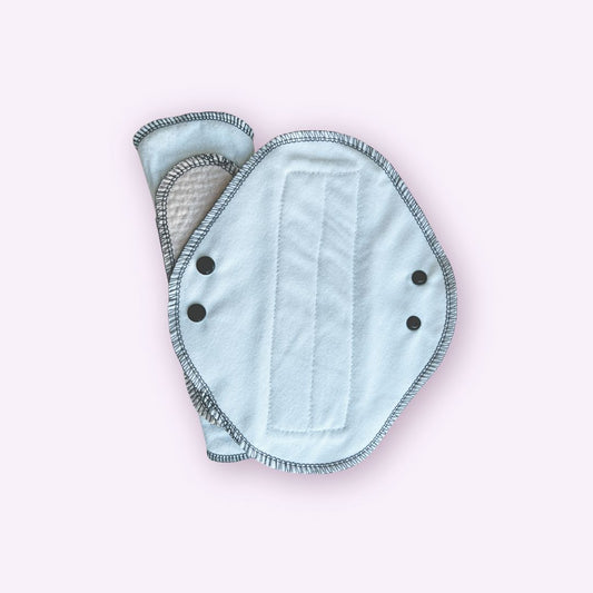 Reusable teen cloth pad in white flannel with double snap wings and absorbent core partially visible