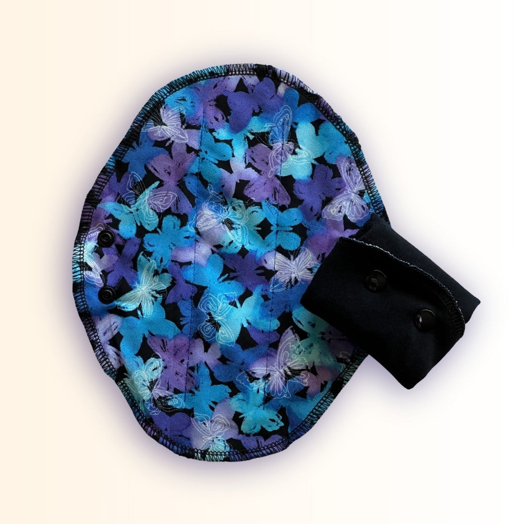Blue butterfly reusable period pad with open print side and folded black cotton absorbent side detail from Hume’s Period Care.