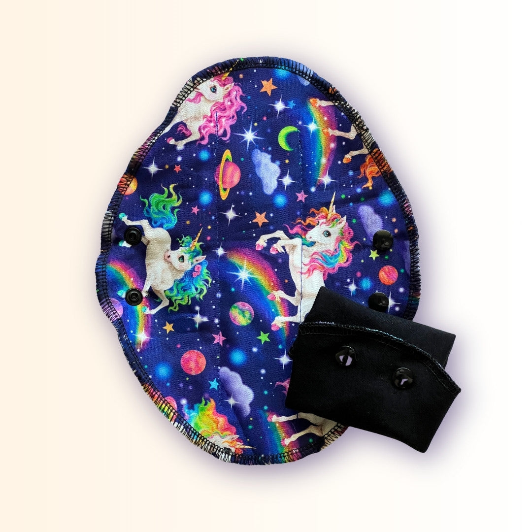 Reusable unicorn period pad with colorful rainbow galaxy print and folded black cotton absorbent side from Hume’s Period Care.